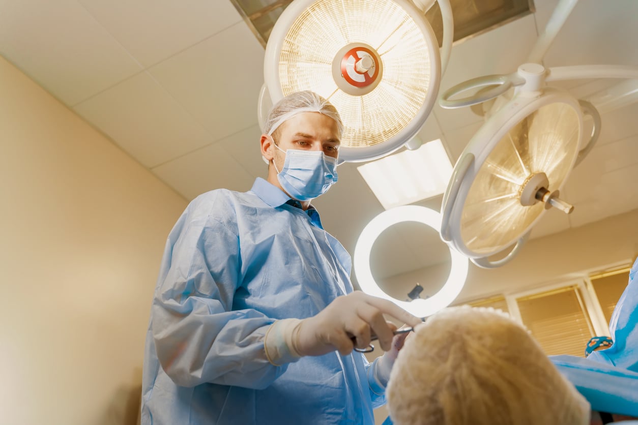 Blepharoplasty plastic surgery operation for modifying the eye region of the face in medical clinic. 2 doctors do plastic cosmetic operation for woman. Surgeon makes an incision with a surgical knife