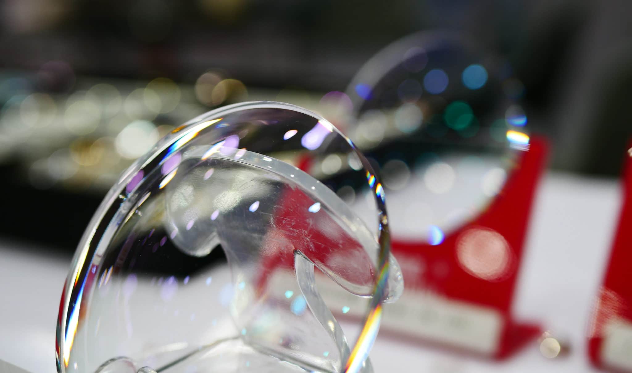 An intraocular lens on a red stand with another blurred in the background.