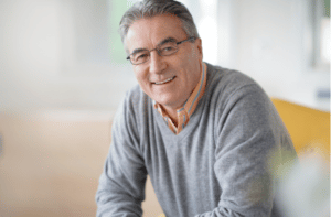 Smiling senior man with eyeglasses relaxing in armchair